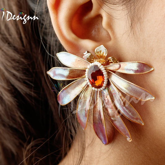 Close-up of a decorative earring worn on an ear, with 'iDesignn' branding.