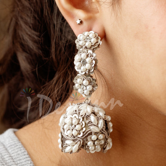 Close-up of a person wearing a pair of ornate silver earrings with a blurred background.