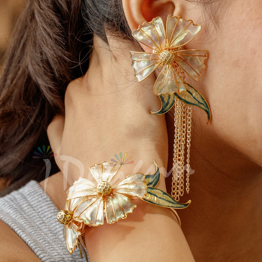 Close-up of a person wearing floral gold earrings with a blurred background