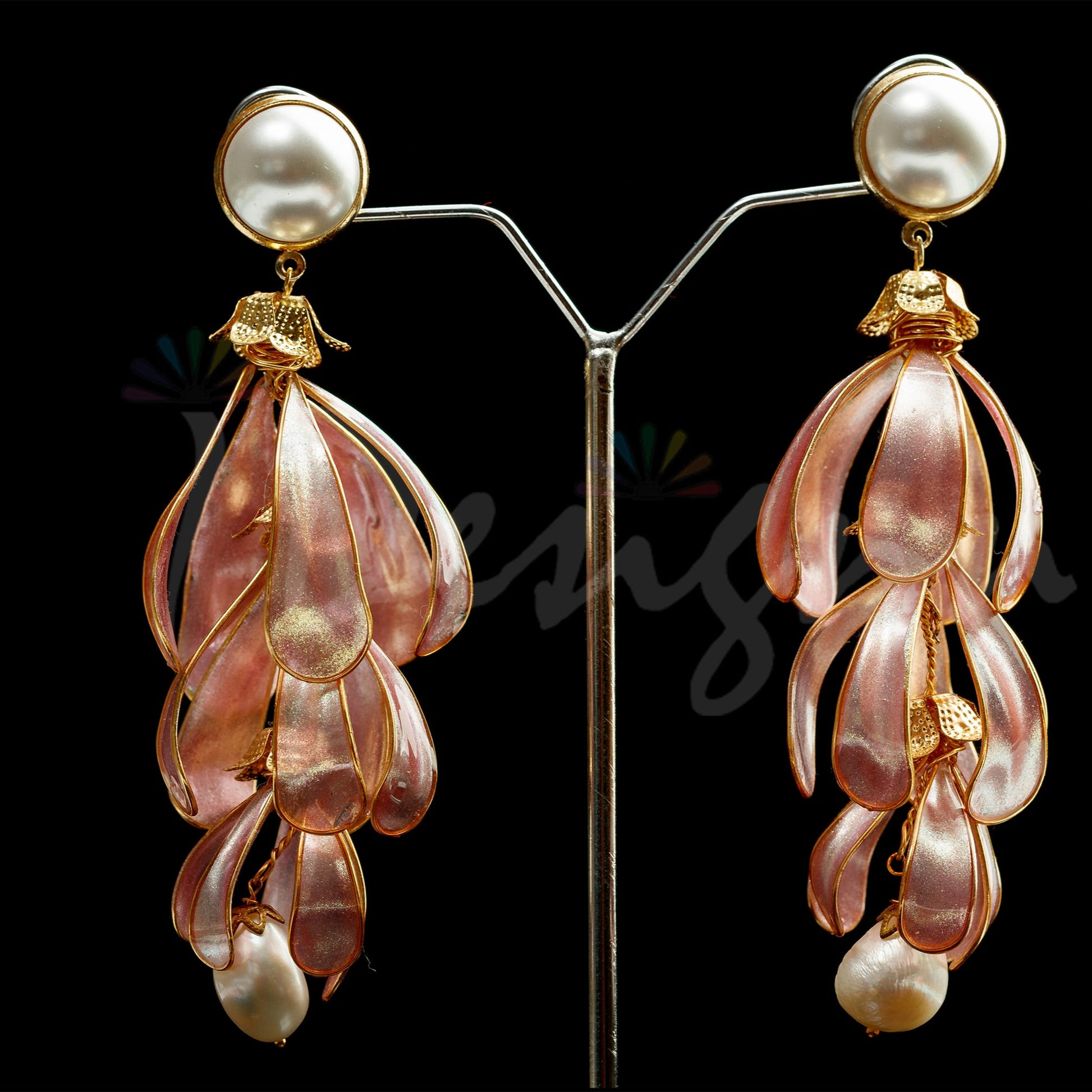 Pair of earrings with pink and gold design on a black background