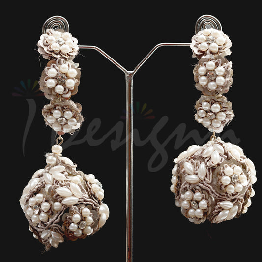 Pair of pearl earrings on a stand against a black background