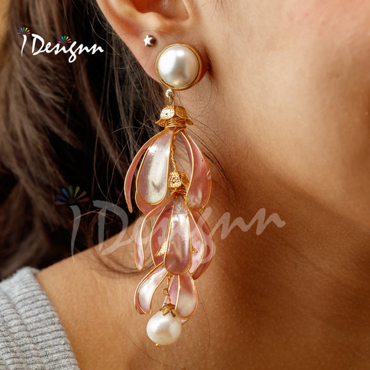 Close-up of a person wearing pink floral earrings with pearl accents.
